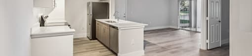 A kitchen with white cabinets and a wooden floor.