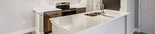 A kitchen with white countertops and wooden floors.