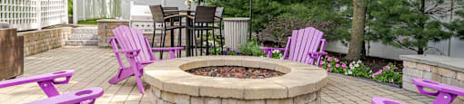 Purple chairs and table around a fire pit in a backyard.