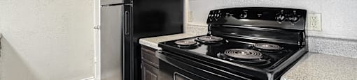 A black stove and refrigerator in a kitchen.