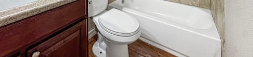 A bathroom with a white toilet, a white bathtub, and a sink with a mirror above it.