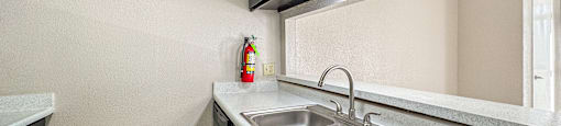 A kitchen with a sink and a fire extinguisher on the wall.