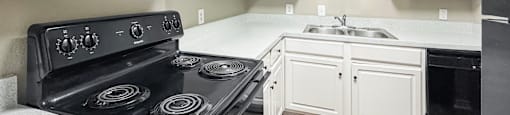 A kitchen with black appliances and white cabinets.