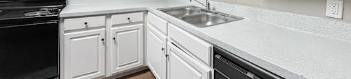 A kitchen with white cabinets and black appliances.