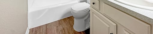 A white toilet sits next to a white bathtub in a bathroom.
