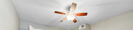 A room with a ceiling fan and light fixture, and a doorway leading to another room.