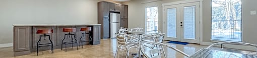 A spacious dining area with a bar and chairs.