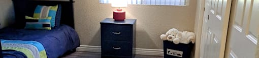 A room with a bunk bed, a nightstand, and a dresser.