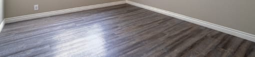 A room with wooden flooring and a window with blinds.