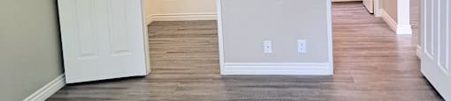 A room with a white door and a wooden floor.