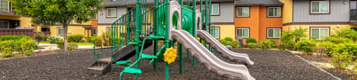 A playground with a green slide and a yellow flower.