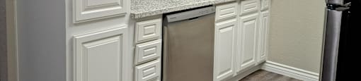 A kitchen with white cabinets and a stainless steel refrigerator.