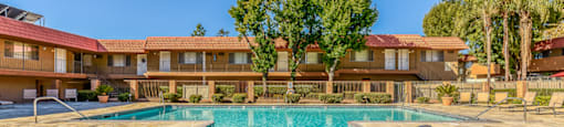 A large swimming pool in front of a building with a red roof.