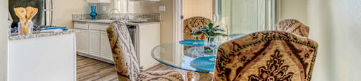 A living room with a brown patterned chair and a glass table.