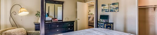 A bedroom with a large bed, a dresser, and a chair.