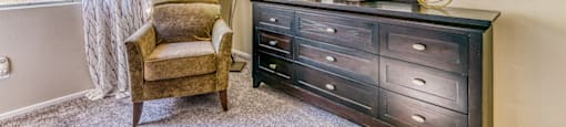A chair, a dresser, and a mirror are in a room.