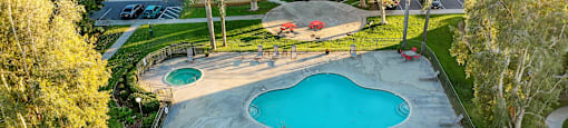 an aerial view of a backyard with a pool and hot tub