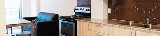 A kitchen with wooden cabinets and a black chair.