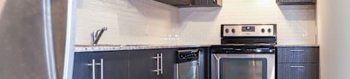 A modern kitchen with dark wood cabinets and stainless steel appliances.