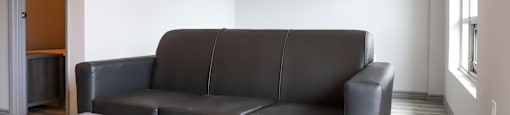 A black leather couch sits in a room with a wooden coffee table.