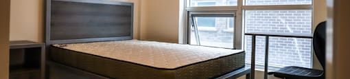 A bedroom with a bed, chair, and window.
