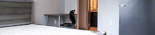 A bedroom with a bed, desk, and chair.