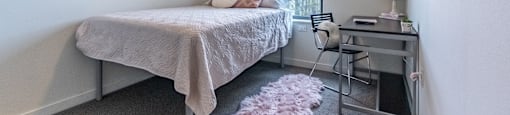 a bedroom with a bed and a desk and a ceiling fan