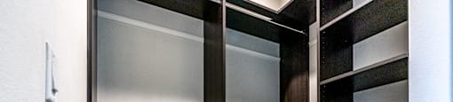 a walk in closet with a dresser and mirrored closet doors