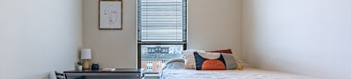 a bedroom with a bed and a desk and a window