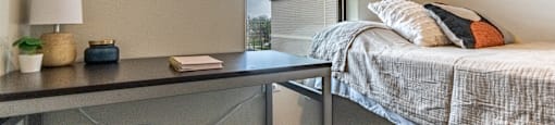 a bedroom with a bed and a desk and a window