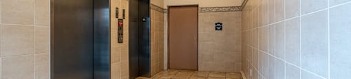 two elevators in a hallway with tiled floors and walls