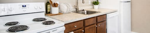 A kitchen with white appliances and wooden cabinets.