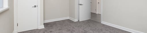A room with a carpeted floor and a ceiling fan.