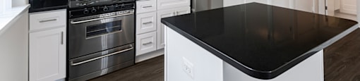 A modern kitchen with a black countertop and stainless steel appliances.