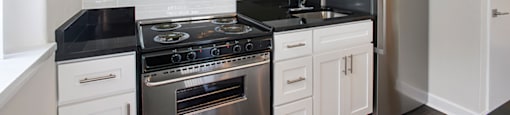 A kitchen with white cabinets and a black countertop.