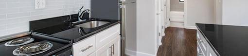 A kitchen with black countertops and white cabinets.