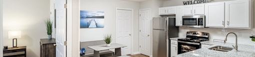 an open kitchen and living room with a kitchen island and stainless steel appliances