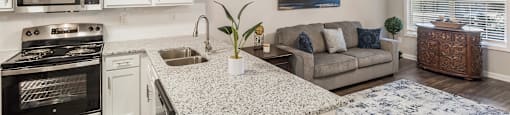 an open kitchen and living room with a granite counter top