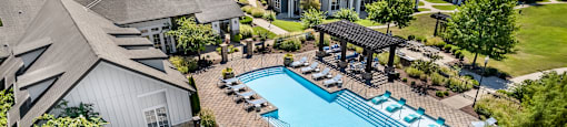 A large outdoor swimming pool surrounded by lounge chairs and umbrellas.