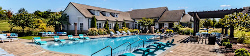 A pool surrounded by sun loungers and a building in the background.