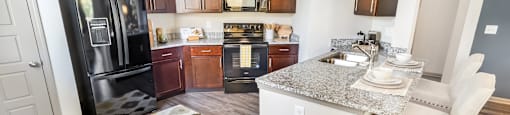 A kitchen with a black fridge and wooden cabinets.