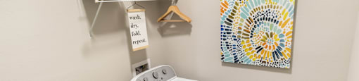 A laundry room with a washer and dryer and a shelf with a sign that says "wash, dry, fold, repeat.".