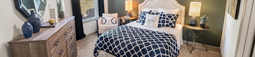 A bedroom with a bed, nightstand, and a mirror on the wall.
