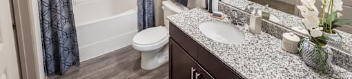A bathroom with a white toilet, a sink, a mirror, and a shower.