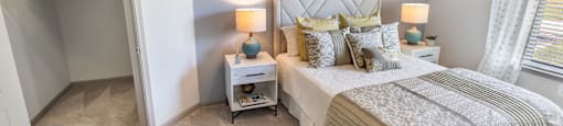 A bedroom with a large bed and a small nightstand with a lamp.