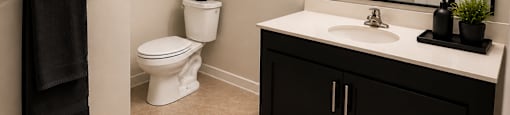 A bathroom with a toilet, sink, and mirror.