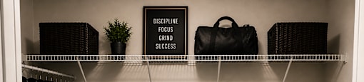 A black and white photo of a closet with a sign that says "Discipline Focus Grind Success".