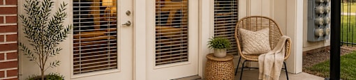 A white door with a glass window is flanked by two potted plants.