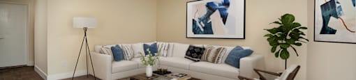 A living room with a white couch, a coffee table, and two abstract paintings on the wall.