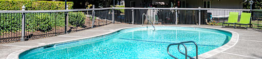 a pool with a fence around it and a house in the background